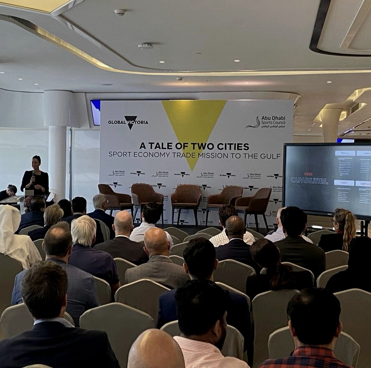 A full room in Abu Dhabi: an audience facing the speaker, with a screen reading “Core capabilities”.